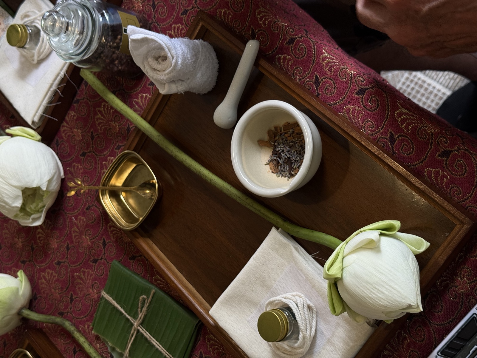Wooden tray with mortar, dried herbs and a lotus bud